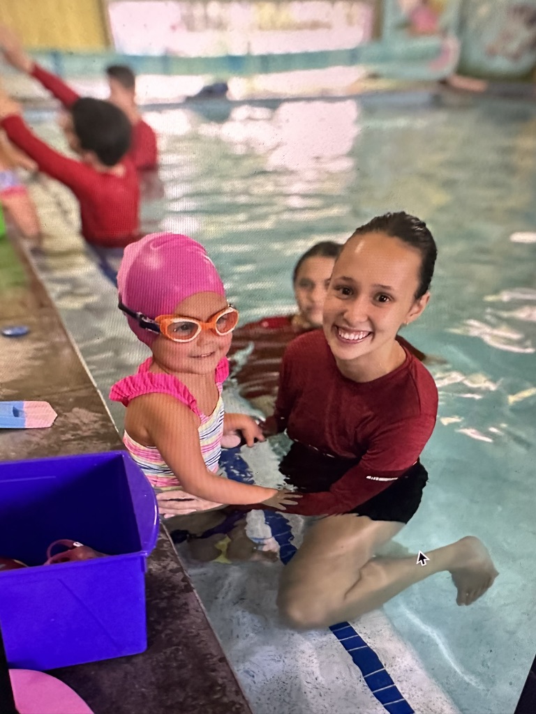 Swim instructor smiling with a student in the pool